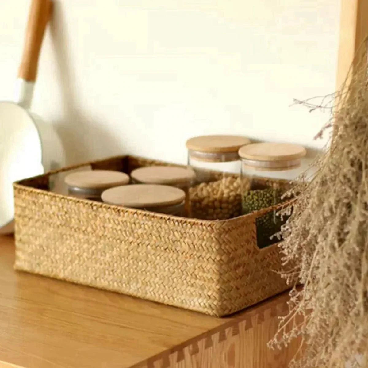 Panier en osier tressé naturel pour rangement cuisine avec pots en verre à couvercle en bois, design léger et pratique.