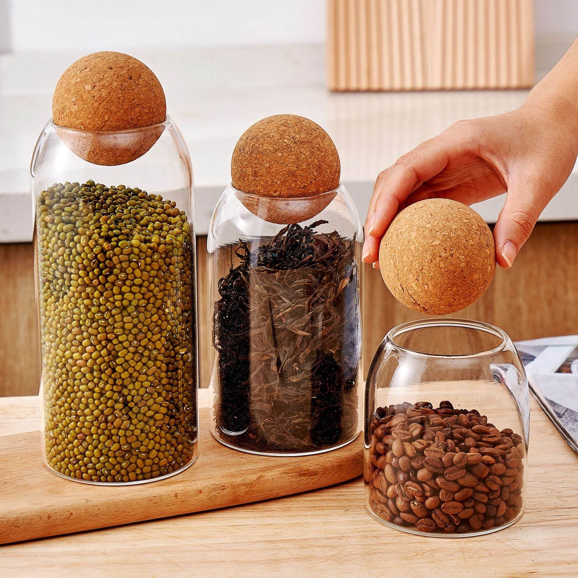 Bocaux en verre transparents avec bouchons de liège naturel remplis de graines, thé et grains de café en lot de 3 pour rangement cuisine.