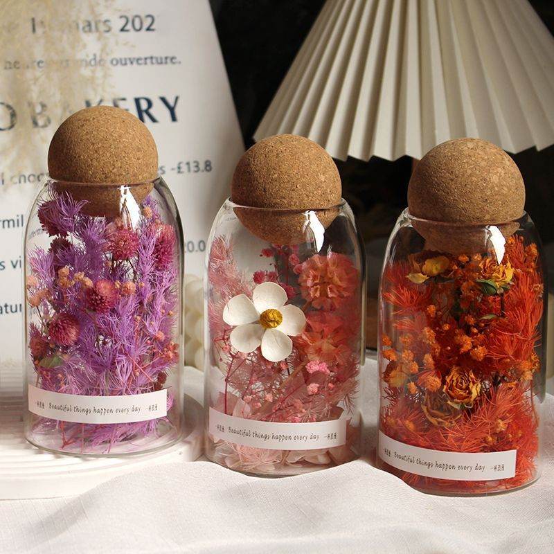 Lot de 3 bocaux en verre avec bouchons de liège contenant des fleurs séchées colorées, parfaits pour la décoration et le rangement.