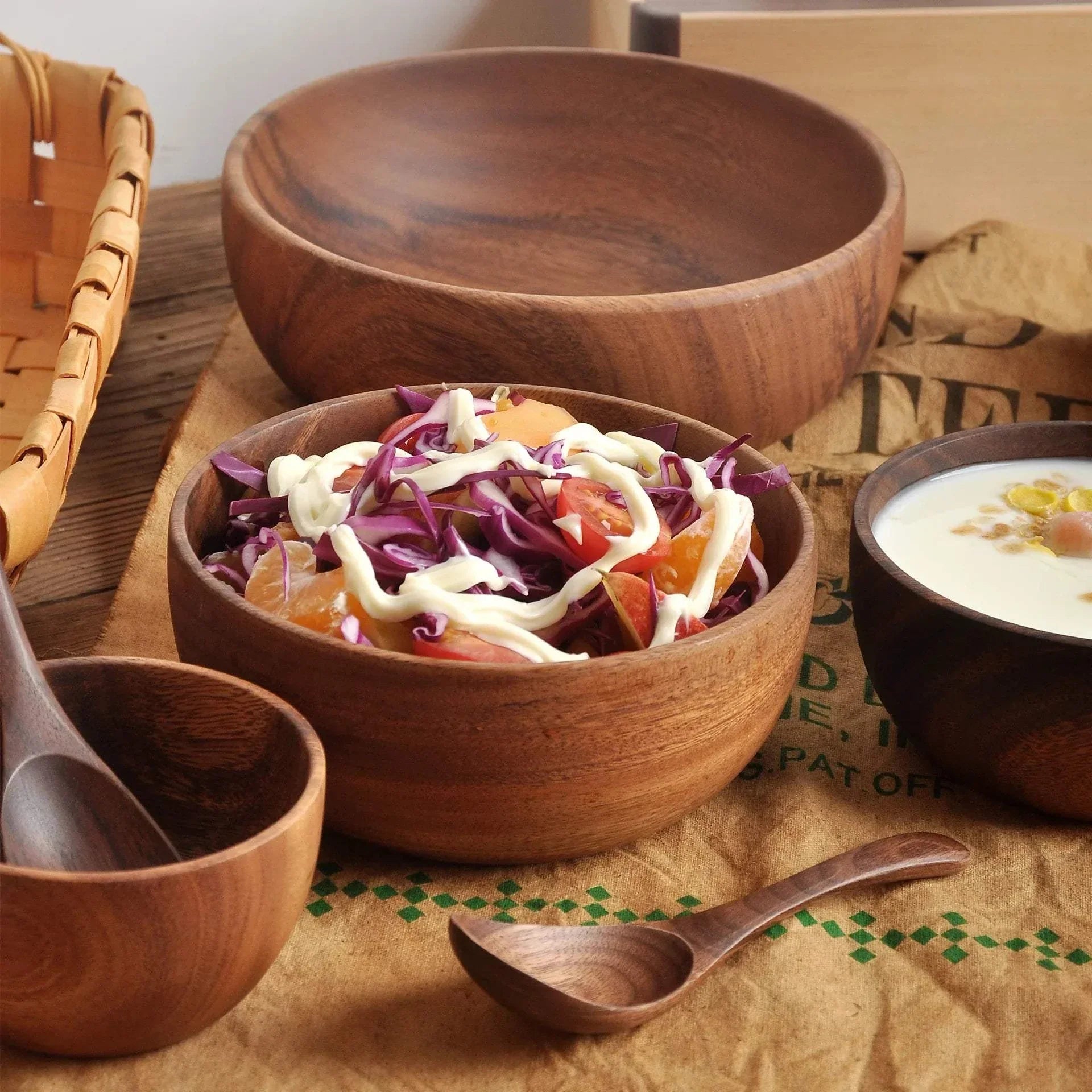 Saladier en bois d'acacia naturel avec salade colorée et sauce mayonnaise, ustensiles assortis sur table rustique