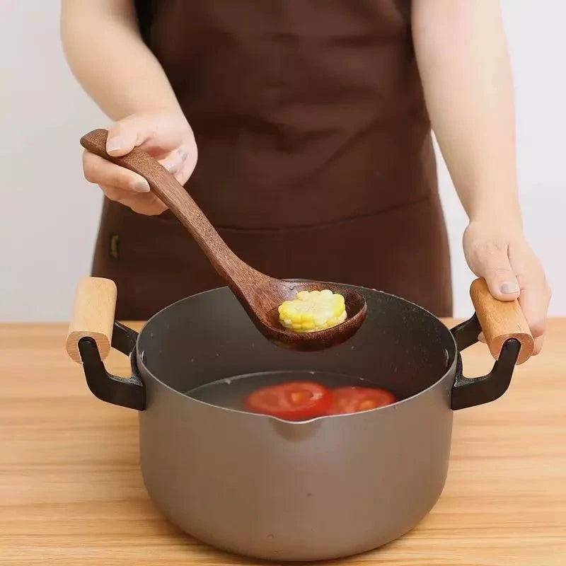 Spatule en bois naturel dans une main, en train de cuisiner avec une casserole contenant des légumes, design élégant et usage durable en cuisine.
