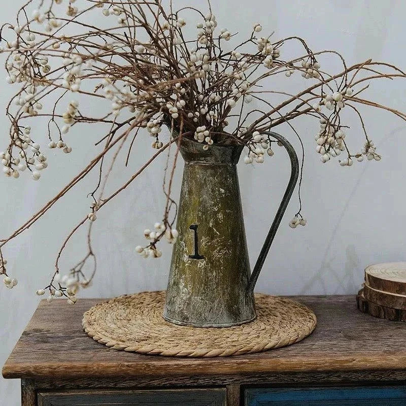 Handwoven round rattan pot mat heat insulation placemat with vintage metal pitcher and dried flowers on wooden table