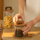 Bocal en verre transparent avec couvercle en bois à anse, idéal pour stocker café ou snacks dans une cuisine organisée et esthétique.