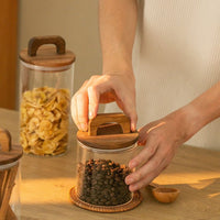 Bocal en verre transparent avec couvercle en bois à anse, idéal pour stocker café ou snacks dans une cuisine organisée et esthétique.