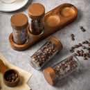 Lot de 4 pots en verre transparents avec bouchons en bois sur une base en bois pour épices ou café.