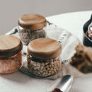 Ensemble de récipients en verre transparent avec couvercles en bois d'acacia remplis de divers aliments secs sur un torchon de cuisine