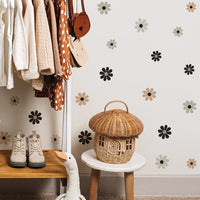 Panier en rotin décoratif en forme de maison champignon dans une pièce avec vêtements suspendus et chaussures sur une étagère bois.