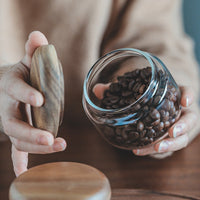 Récipient de conservation alimentaire en verre transparent avec couvercle en bois d'acacia contenant des grains de café, pour une organisation pratique et élégante de la cuisine.
