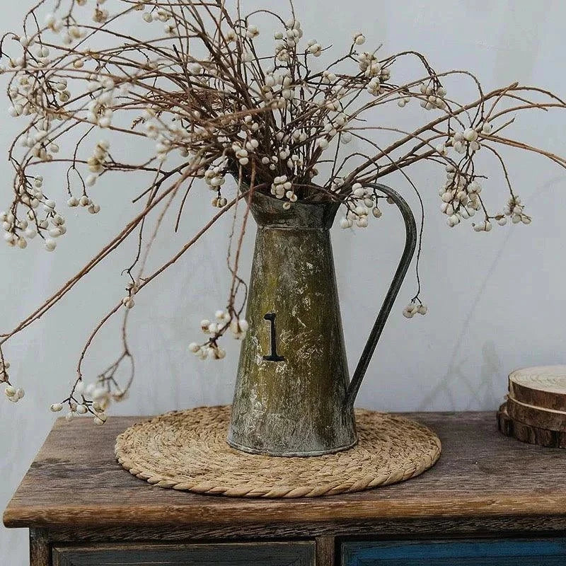 Handwoven round rattan pot mat heat insulation placemat with vintage metal pitcher and dried flowers on wooden table