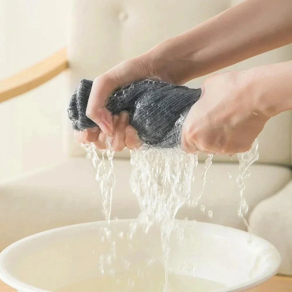 Soft absorbent gray cotton dishcloth being wrung over a white bowl with water flowing out