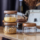 Ensemble de récipients alimentaires en verre transparent avec couvercles en bois d'acacia sur une surface en bois, contenant du millet jaune et des graines de soja, idéal pour organiser votre cuisine et garantir la durabilité.